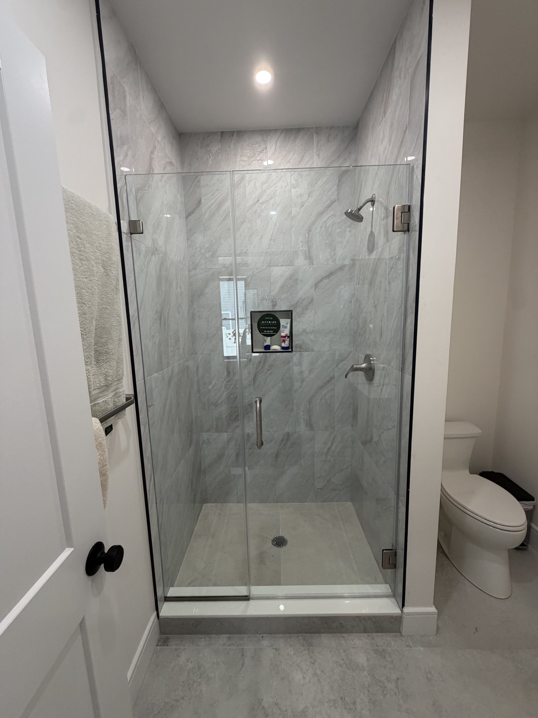 Custom frameless glass shower enclosure in a marble bathroom